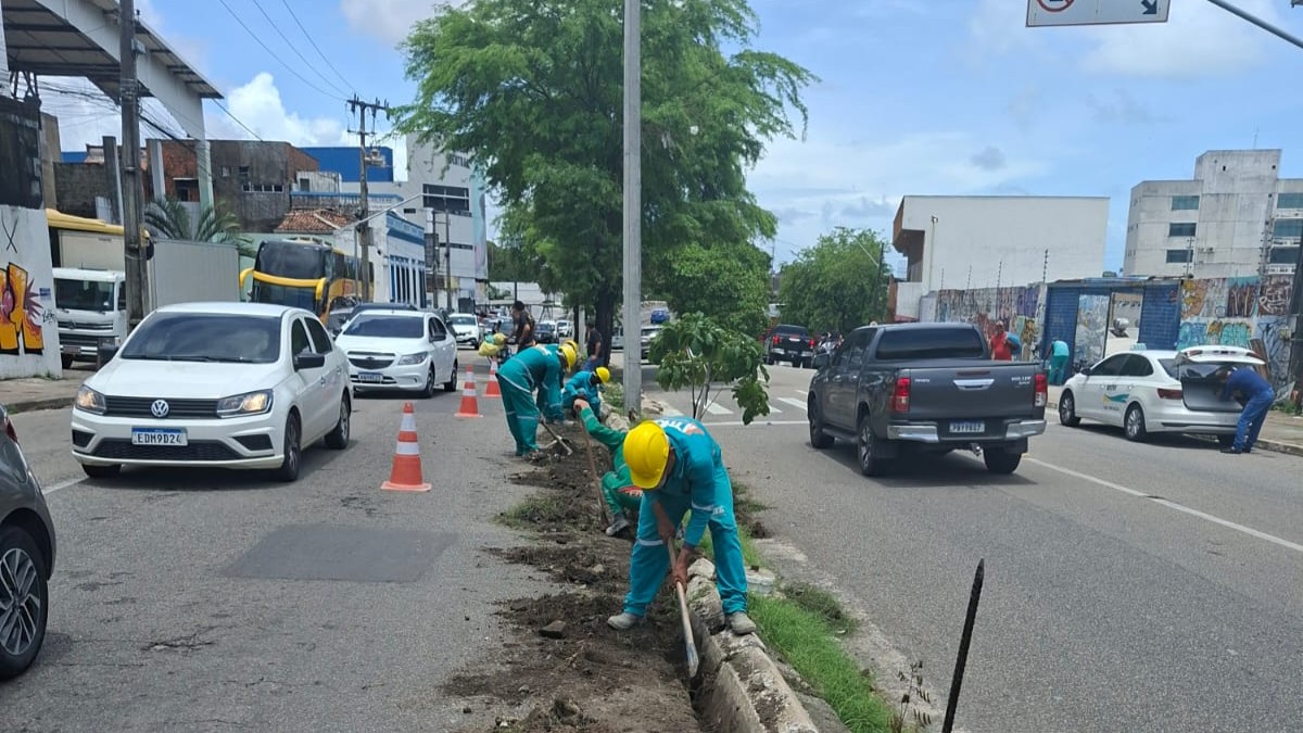 Homens consertando o meio-fio de uma avenida
